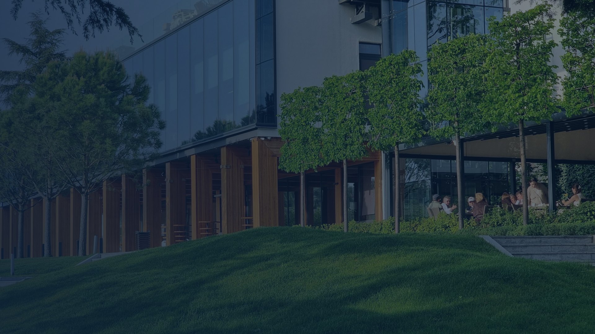 Manicured commercial lawn and tree-lined glass office building, an example of professional commercial landscaping in Grayson, GA