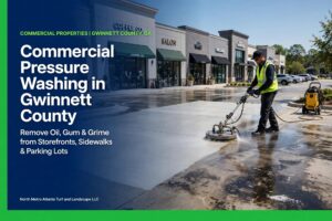 Technician in a high-visibility vest using a surface cleaner to pressure wash a parking lot in front of a Gwinnett County, GA strip mall